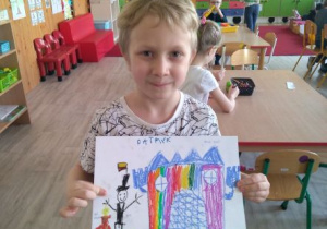 Chłopiec z rysunkiem przedstawiającym łódzki pałac Misia Uszatka i łódzkiego Mima z ulicy Piotrkowskiej